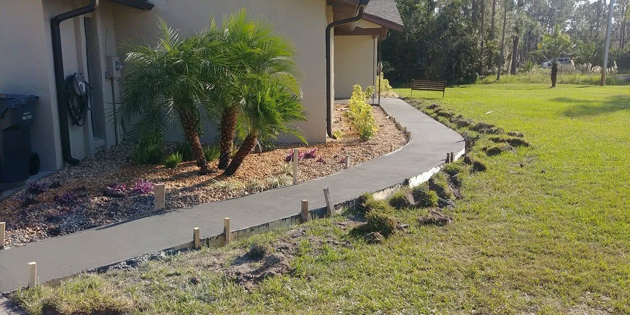 Curved concrete sidewalk through a landscaped yard